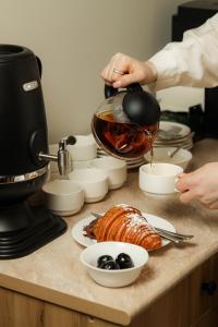 une personne versant du café dans une cafetière sur un comptoir où se trouvent des aliments dans l'établissement Barca Hotel, à Erevan