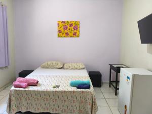 een kleine slaapkamer met een bed en een schilderij aan de muur bij Aquarela Suítes in Piúma