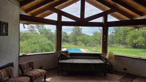 een kamer met een groot raam met uitzicht op een zwembad bij Atardecida in Villa Las Rosas