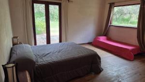 een slaapkamer met een bed, een bank en ramen bij Atardecida in Villa Las Rosas +10 foto's