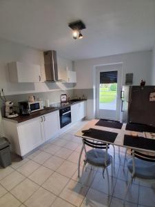 een keuken met witte kasten en een tafel met stoelen bij La Ferme du moulin in Montaigu-Vendée