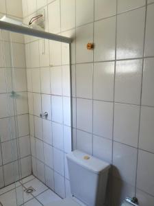 een witte badkamer met douche en toilet bij Aquarela Suítes in Piúma