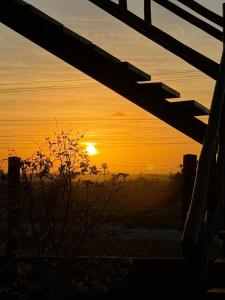 Een zonsondergang door een houten hek met de zon op de achtergrond. bij Suítes Taipu de Fora in Marau