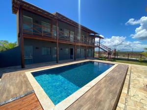 a house with a swimming pool in front of a building at Suítes Taipu de Fora in Marau