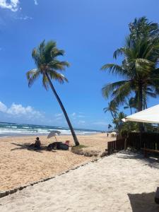 een persoon die onder een parasol op het strand zit bij Suítes Taipu de Fora in Marau