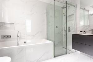 ein weißes Badezimmer mit einer Dusche, einer Badewanne und einem Waschbecken in der Unterkunft Metro Luxe Suites in Porto Cervo