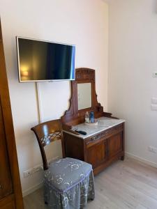 een kamer met een bureau, een televisie en een stoel bij Artemide Relais in Montebelluna