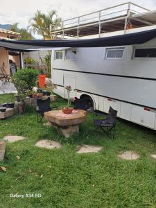 een camper geparkeerd in een tuin met een tafel en stoelen bij Bbzao motor home in São Sebastião