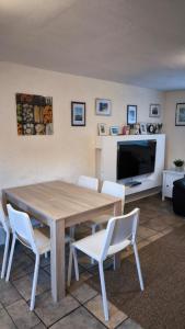 een eettafel met witte stoelen en een televisie bij Holiday Apartment in Oberveischede