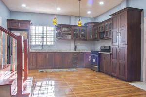 a large kitchen with wooden cabinets and a wooden floor at Garden View Villa in Georgetown +7 photos