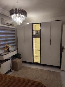 een kamer met witte kasten en een kroonluchter bij Myhouse in Ariana