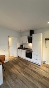 an empty kitchen with white cabinets and a table at Mühls Apartments in Bad Lauterberg +14 photos