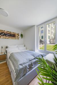 a white bedroom with a large bed and a window at Urban Hideaway Studio St Gallen Center Self Check-In in St. Gallen