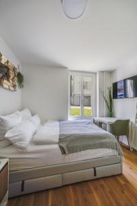 a white bedroom with a large bed and a window at Urban Hideaway Studio St Gallen Center Self Check-In in St. Gallen