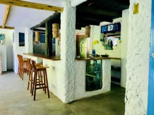 a kitchen with a counter and stools in a room at Vila Iemanjá in Cumuruxatiba