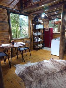een kamer met een tafel en stoelen en een koelkast bij Cabana Montana in Córrego do Bom Jesus