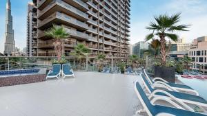 a patio with chairs and a pool with a building at Spacious & cozy Studio in Downtown! in Sabkhah