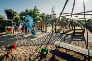un parc avec une aire de jeux avec un toboggan et un banc dans l'établissement Camping le Moulin des Oies, à Belz