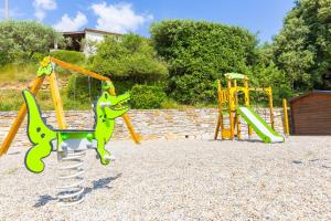 a playground with two swings and a slide at Village de gîtes La Fontinelle in Bessas