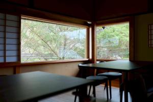 two tables and chairs in a room with a window at 結びの小宿 縁 by Wellbe in Kobe