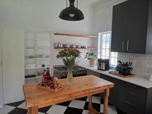 een keuken met een tafel met daarop een vaas met bloemen bij Quaint Muizenberg Stay and Private Suite in Muizenberg