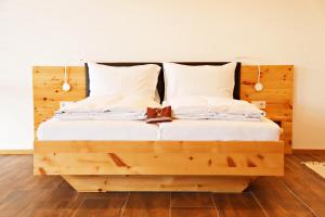 - un lit en bois avec des draps et des oreillers blancs dans l'établissement Lässerhof, à Hub