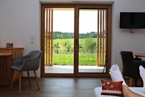 une personne allongée sur un canapé regardant par une porte coulissante en verre dans l'établissement Lässerhof, à Hub 3 autres photos