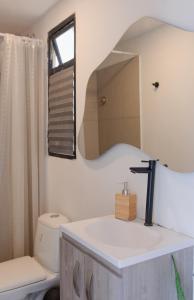 een badkamer met een wastafel, een toilet en een spiegel bij Villa Malibu in Santa Marta