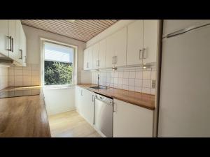 una cucina vuota con armadi bianchi e una finestra di Plads til børnefamilien i hjertet af Esbjerg a Esbjerg