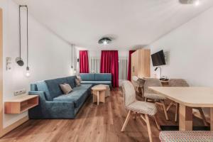 een woonkamer met een blauwe bank en een tafel bij Hotel Dominic in Sölden