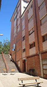 dos bancos frente a un edificio de ladrillo con escaleras en Hostal Valle De Tena, en Sabiñánigo