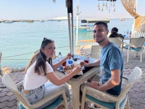 a man and a woman sitting at a table by the water at Al-Amer Aqaba Beach Hostel in Aqaba