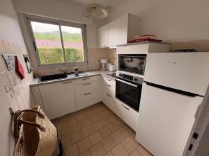 a kitchen with a white refrigerator and a window at Albizias 3 in Eugénie-les-Bains +6 photos