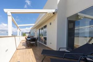 un balcone con tavoli e sedie in un edificio di Design Luxury Penthouse with Private Pool a Żurrieq
