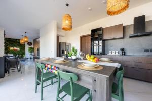una cucina con un grande tavolo di legno e sedie verdi di Design Luxury Penthouse with Private Pool a Żurrieq