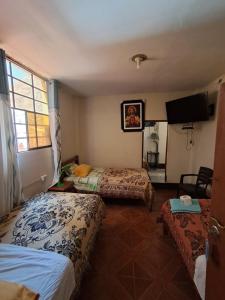una camera d'albergo con due letti e una televisione di Hostal la familia a Churín