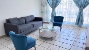 een woonkamer met een bank, twee stoelen en een tafel bij Croydon Vista Luxe in Kempton Park +2 foto's
