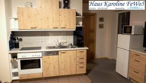 a kitchen with wooden cabinets and a sink and a refrigerator at Haus Karoline FeWo5 in Hochrindl