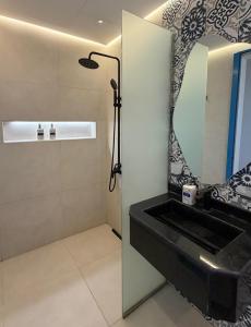 een badkamer met een zwarte wastafel en een spiegel bij Santorini check in in Ras al Khaimah