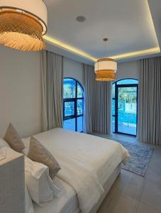 een slaapkamer met een groot wit bed en twee ramen bij Santorini check in in Ras al Khaimah