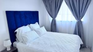 een slaapkamer met een wit bed met een blauw hoofdeinde en een raam bij Croydon Vista Luxe in Kempton Park