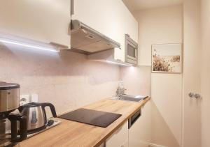 een kleine keuken met een spoelbak en een magnetron bij Strandliebe in Scharbeutz, stilvolle Ferienwohnung, 150m zum Strand! Sonnenbalkon, ruhig gelegen, kostenfreier Parkplatz, Fahrstuhl in Scharbeutz