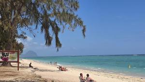 a group of people sitting on a beach at Rayon Bleu A3 two bedroom apartment-perfect sea escape! in Flic-en-Flac