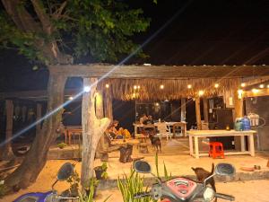 een groep mensen die 's nachts op een patio zitten bij Phayam Hostel in Ko Phayam