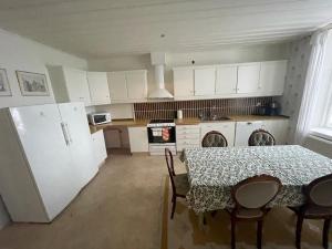 eine Küche mit einem Tisch und Stühlen sowie weißen Schränken in der Unterkunft Spacious and charming apartment in central Storvik in Storvik