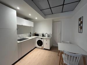 a kitchen with white cabinets and a washer and dryer at Le cocon avec Terrasse in Amiens