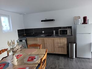 een keuken met een tafel en een witte koelkast bij Maison La Tour Penchée in Oye-Plage