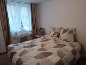 een slaapkamer met een bed met een dekbed en een raam bij Maison La Tour Penchée in Oye-Plage