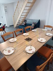 een grote houten tafel met borden en glazen erop bij Maison La Tour Penchée in Oye-Plage
