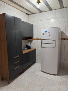 een keuken met een witte koelkast en zwarte kasten bij Casa Praia Japaratinga in Japaratinga